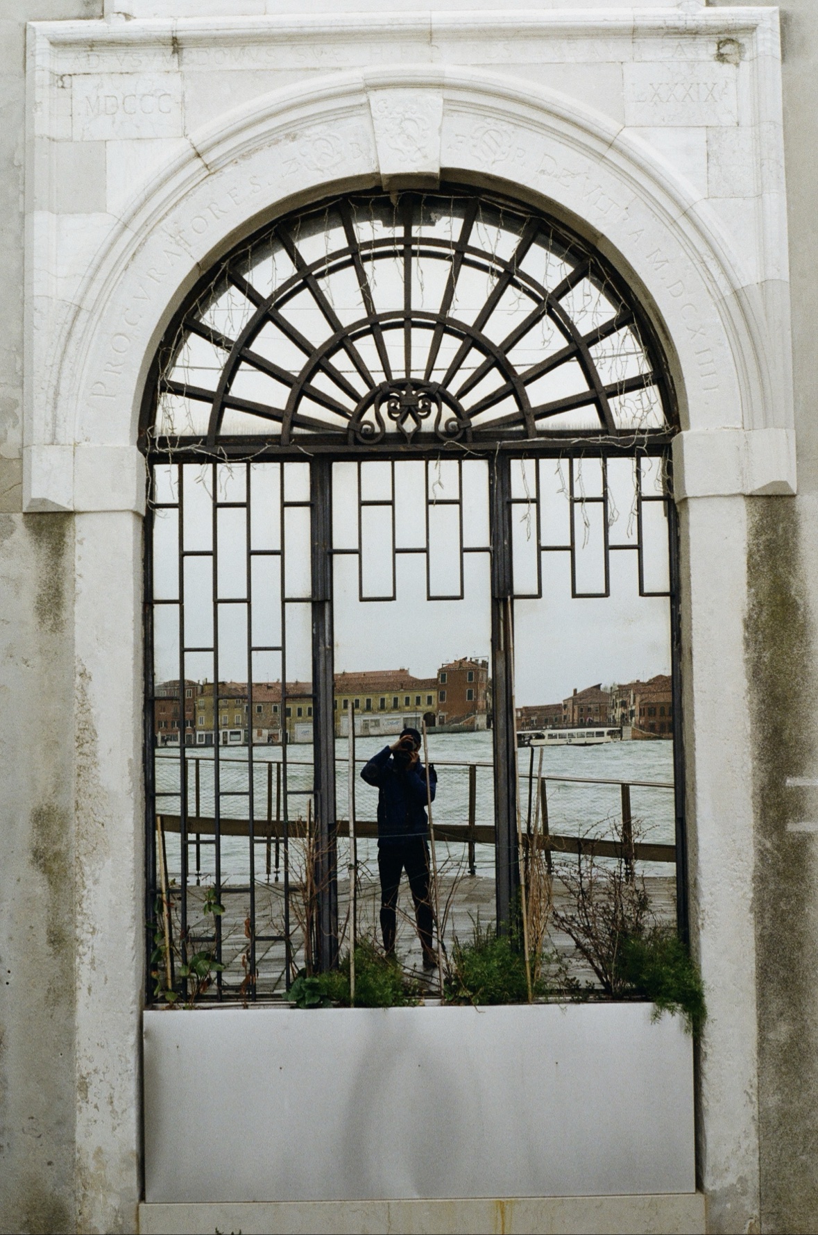 A person standing at an iron gate overlooking the Venetian lagoon